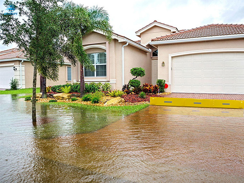 Yellow PVC flood barrier blocks floodwater outside residential garage door