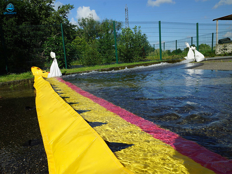 Yellow self-rising flood barrier holding back water