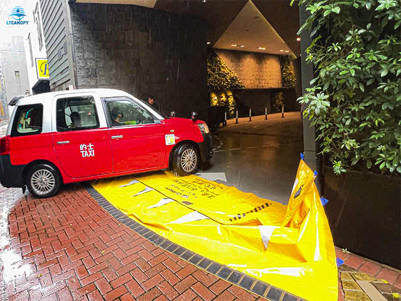 Yellow water gate flood barrier allowing car passage at building entrance