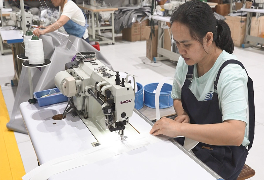 Worker performing reinforced stitching on fabric with industrial sewing machine