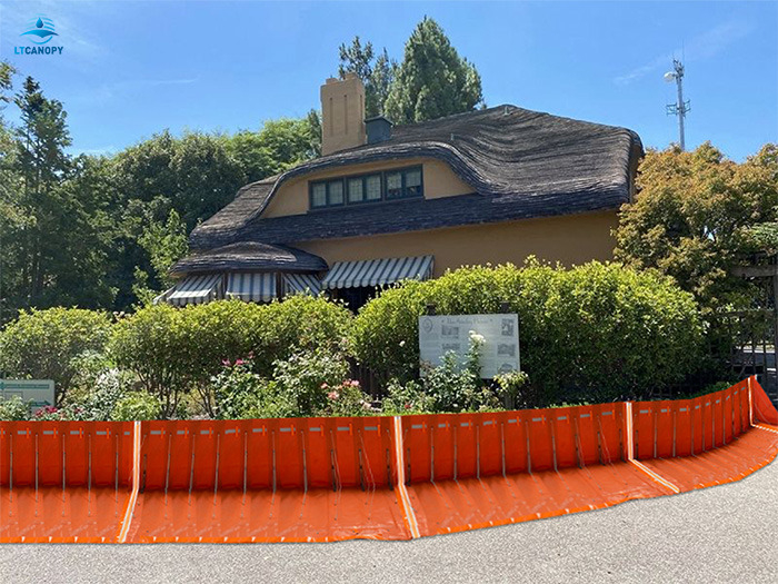 Orange modular flood barrier installed around a residential house, flexible PVC system for home flood defense