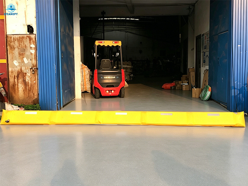 Yellow reusable flood barrier installed at industrial warehouse doorway